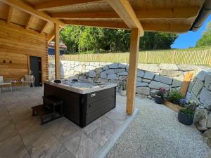 an outdoor patio with a grill and a stone wall at Luxus Chalet Zur Resi in Mauth