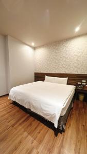 a large white bed in a room with a wooden floor at Tomorrow Hotel in Taipei