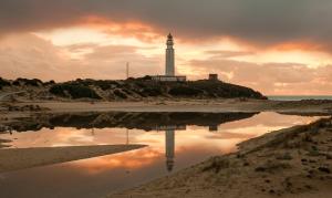 a lighthouse on a beach with a reflection in the water at Casa en casco antiguo de Barbate in Barbate