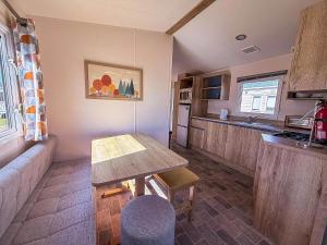 a small kitchen with a table and a couch at Lovely 6 Berth Caravan Close To The Beach In Suffolk Ref 68030Bs in Lowestoft
