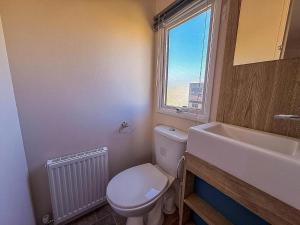 a bathroom with a toilet and a sink and a window at Lovely 6 Berth Caravan Close To The Beach In Suffolk Ref 68030Bs in Lowestoft +11 photos