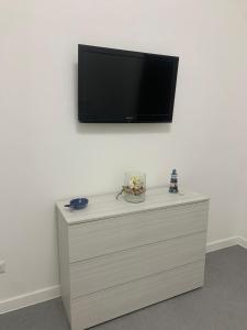 a dresser with a tv on a white wall at Volver Apartment in Margherita di Savoia