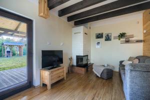 a living room with a flat screen tv and a couch at Domki Omulew in Wikno