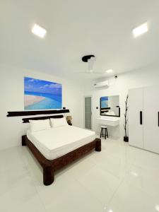 a white bedroom with a bed and a painting on the wall at Crystal sea inn in Bileffahi