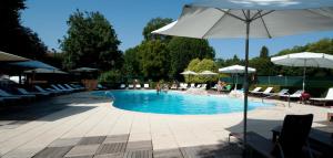 una piscina con sillas y sombrilla en Albergo Belvedere, en Sequals