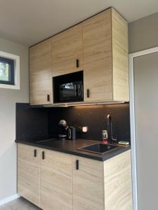 a kitchen with wooden cabinets and a microwave at Hélius lodge in Brugelette