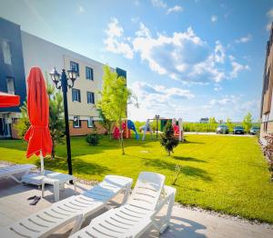 a group of chairs and umbrellas next to a park at Airport Gardens Loft in Otopeni