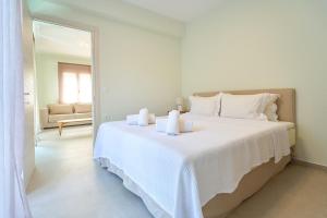 a white bedroom with a large bed with white sheets at Zoe's Luxury Apartment in Xanthi