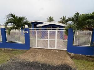 a blue fence with palm trees in front of a house at Silagi Holiday Home in Nadi