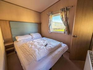 a small bedroom with a bed and a window at Fantastic Caravan With Decking At Haven Hopton Holiday Park Ref 80069G in Great Yarmouth +12 photos