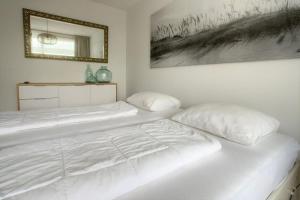 1 dormitorio con 1 cama blanca y 2 almohadas en Duinroosje, en Cadzand