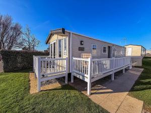 a mobile home with a white fence on a yard at Fantastic Caravan With Decking At Haven Hopton Holiday Park Ref 80069G in Great Yarmouth