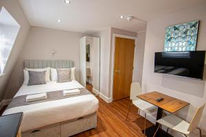 a bedroom with a bed and a table and a television at Imperial Court Studios in London