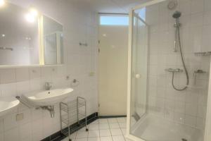 Un baño blanco con ducha y lavabo. en Duinroosje, en Cadzand 14 fotos más