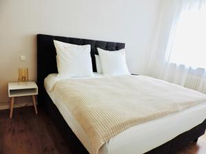 - un lit avec une tête de lit noire ainsi que des draps et des oreillers blancs dans l'établissement Julia's Mosel Villa Appartement JULIA, à Traben-Trarbach