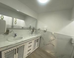 a white bathroom with two sinks and a mirror at Guesthouse Los Geranios in Mocanal