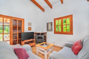 Una sala de estar con un sofá y un televisor. en Tintorer, en Puerto Pollensa