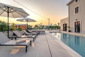 a swimming pool with lounge chairs and an umbrella at Luxury Villa Madora with pool in Porec, Istria in Krmenjak