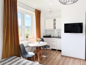 a room with a kitchen and a table with chairs at Pokoje i apartamenty Ferencówka Bieszczady in Zawóz