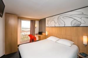 um quarto de hotel com uma cama branca e uma janela em ibis Roscoff em Roscoff
