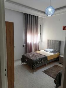 a bedroom with a bed in a room with a window at Le bon sejour in El Aouina Station