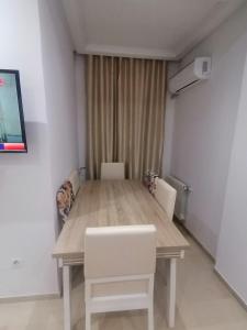 a dining room table with white chairs and a television at Le bon sejour in El Aouina Station +10 photos