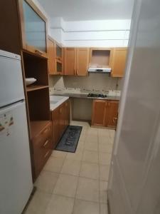 a kitchen with wooden cabinets and a white refrigerator at Le bon sejour in El Aouina Station