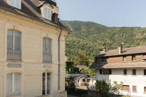 an old house in a town with mountains in the background at Vacances cures luchon in Luchon