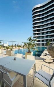 a white table and chairs on a patio with a building at Mamaia Luxury Studio Apartment T in Mamaia