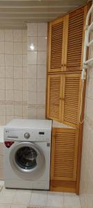 a washing machine in a kitchen with wooden cabinets at Avar korter Kuressaare südames in Kuressaare