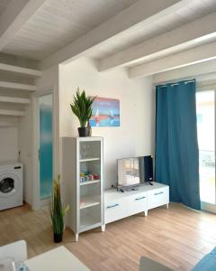 ein Wohnzimmer mit einem weißen Schrank und einem TV in der Unterkunft Affittimoderni Isola Rossa Borgo - Ulivi 9 in Isola Rossa + 24 Fotos