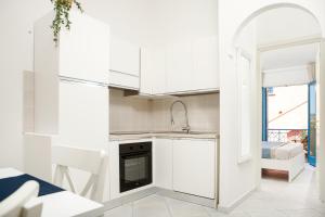 a white kitchen with a sink and a stove at BILANCIA V 30' Porto Cervo & PRIVATE TERRACE with SEA VIEW in Porto Pozzo