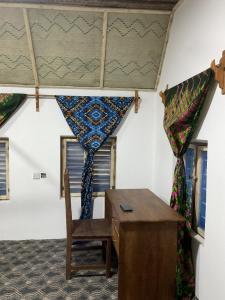 a room with a desk and a table and curtains at JozaniBiospherevillage in Jozani