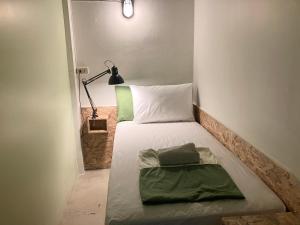 a small bed in a small room with a lamp at 326 Podtel at The Breakie Bar in Bangkok