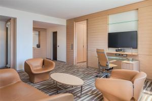 a hotel room with a flat screen tv and chairs at Hilton Frankfurt Airport in Frankfurt/Main