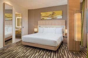a bedroom with a large white bed and a mirror at Hilton Frankfurt Airport in Frankfurt/Main