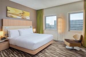 a bedroom with a bed and a desk and two windows at Hilton Frankfurt Airport in Frankfurt/Main
