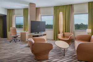 a hotel room with a tv and chairs and a flat screen at Hilton Frankfurt Airport in Frankfurt/Main