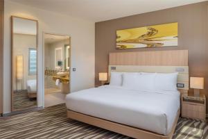 a bedroom with a large white bed and a mirror at Hilton Frankfurt Airport in Frankfurt/Main