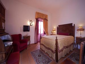 a bedroom with a bed and a chair and a television at Betica Hotel Rural in Pias