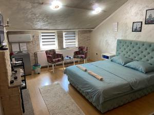 a bedroom with a large bed with a blue headboard at President app Arandjelovac in Arandjelovac