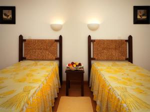 two beds in a room with a bowl of fruit on a table at Betica Hotel Rural in Pias