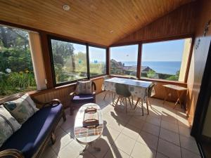 Zimmer mit Sofa, Tisch und Fenstern in der Unterkunft Évasion bretonne au bord de l'eau in Plouguerneau