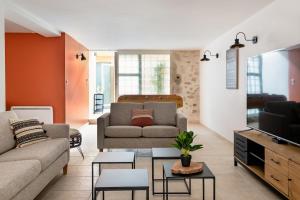 a living room with a couch and a tv at Évasion de charme, maison authentique et spa privé in La Baume-de-Transit
