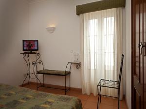 a bedroom with a bed and two chairs and a television at Betica Hotel Rural in Pias
