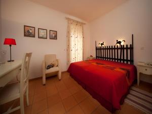 a bedroom with a red bed and a desk at Betica Hotel Rural in Pias