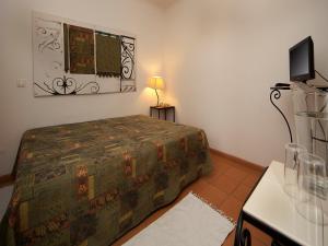 a small bedroom with a bed and a television at Betica Hotel Rural in Pias