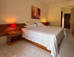 a bedroom with a large white bed with a red lamp at Παντέλειο in Karistos +5 photos