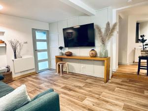 a living room with a tv and a wooden floor at Peaceful and Stylish Garden Flat Close to Transport and City Centre in Glasgow