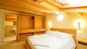 una camera da letto con un letto bianco con un soffitto in legno di Destiny Home & rooms Soave a Soave